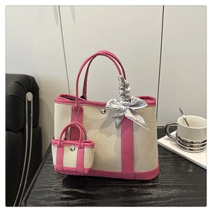 Detail of canvas tote bag featuring pink leather trim, a mini bag charm, and silk scarf