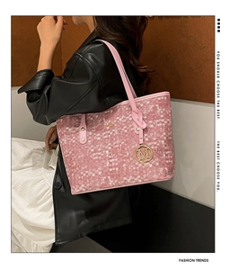 Détail du sac fourre-tout tissé rose avec breloque dorée en M sur la bandoulière