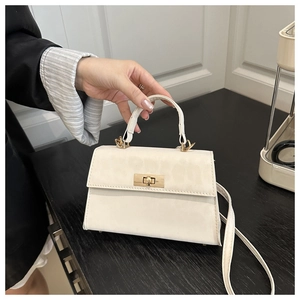 Detail of white matte crossbody bag with golden twist lock and thin leather shoulder strap