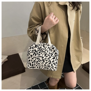 Detail of leopard print corduroy lunch bag shown with a beige coat in a daily scene