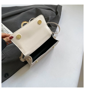 Internal view of cream square flap bag with dual magnetic buckles and gold hardware