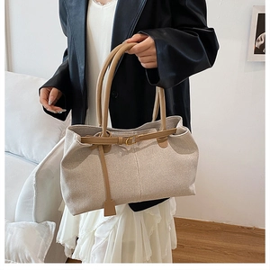 Close-up of a canvas and brown leather stitching tote bag with metal buckle details
