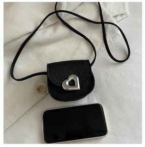 Detailed view of black litchi leather mini bag with a silver heart-shaped metal buckle