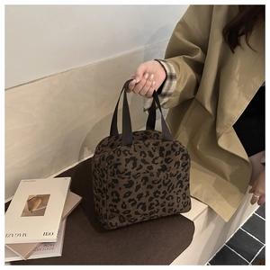 Close-up of leopard print corduroy lunch bag with black ribbon handles in lifestyle setting