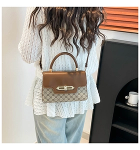 Detailed view of vintage patchwork shoulder bag with metallic clasp worn by a model