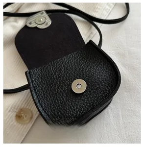 Detail of the high-quality lychee grain leather and metal magnetic clasp on a black bag