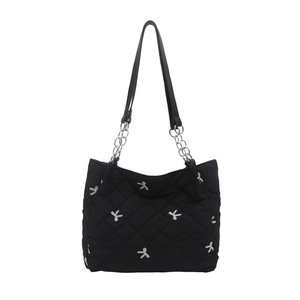 Quilted tote bag with silver bow embroidery and chain strap detail on white background