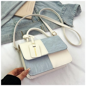 Macro shot of blue pleated leather texture and gold hardware on two-tone crossbody bag