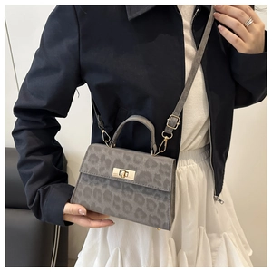 Detail of grey leopard print bag with golden clasp and adjustable shoulder strap