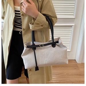 Close-up of stylish large canvas tote bag with black leather straps and gold buckle