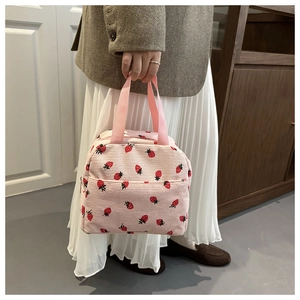 Pink corduroy lunch bag with strawberry print showing handheld straps and soft texture