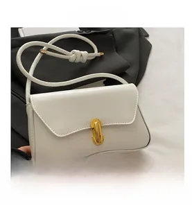 Detail of white leather handbag with golden pillar lock and sleek cord shoulder strap