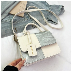 Detail of color-block leather crossbody bag with silver metallic panels and hangtag