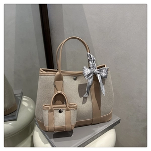 Detail of canvas tote bag with brown leather handles and decorative heart pattern silk scarf