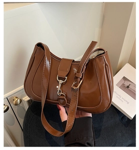 Close-up of caramel brown glossy patent leather shoulder bag with metallic buckle detail