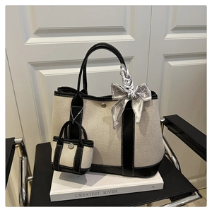 Detail of canvas tote bag set with black leather trim and decorative silk scarf handles