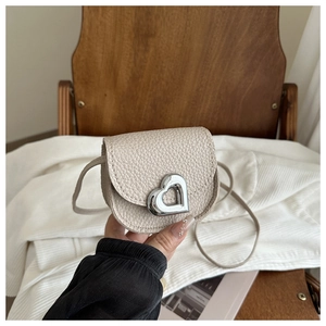Détail du mini sac bandoulière en cuir grainé avec boucle métallique en forme de cœur