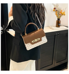 Detail of a vintage-style patchwork crossbody bag with gold-tone metal twist lock