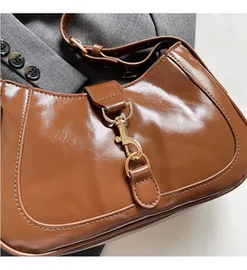 Close-up of caramel glossy leather bag with oversized golden lobster clasp hardware