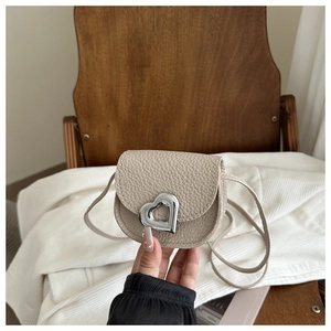 Detail der silbernen Herzschnalle auf der cremeweißen Mini-Tasche aus Kieselleder