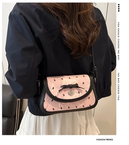 Gros plan du sac plissé rose avec motifs papillons noirs et pendentif en forme de coeur