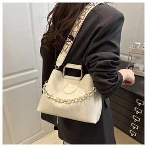 Dettaglio borsa in pelle crema con manico dorato, catena e tracolla jacquard con logo