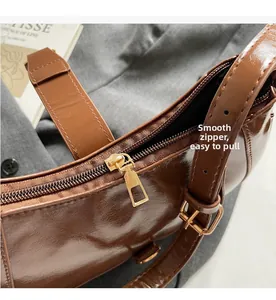Detail of a smooth golden zipper and polished buckle on a brown baguette bag