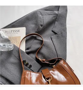 Close-up of brown glossy crescent bag with gold hardware and stylish shoulder strap
