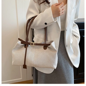 Detail of a large canvas tote bag with brown leather straps shown on a shoulder