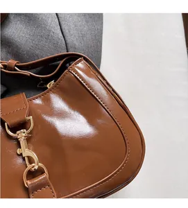 Detail of glossy brown faux leather handbag with high-quality golden metal lobster clasp