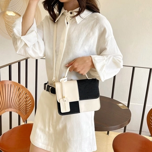 Fashionable black and white contrast shoulder bag with top handle and crossbody strap