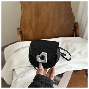 Détail d'un mini sac bandoulière en cuir noir avec une boucle argentée en forme de cœur