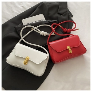 Close-up of sleek leather flap bags in red and white with gold capsule metal buckles