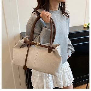 Close-up of cream canvas tote bag with brown leather straps and gold metal buckles