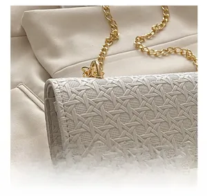 Detail of beige woven texture handbag with light gold metal chain and hardware