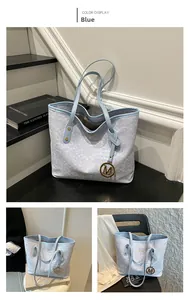 Vue détaillée d'un sac cabas bleu clair avec texture fine et pendentif métallique en M