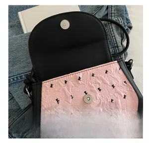 Gros plan du fermoir magnétique en métal sur un sac à bandoulière rose à motifs