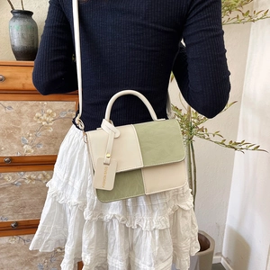 Contrast color box crossbody bag in cream and green held by model in home setting
