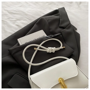 Detail of white leather handbag featuring gold metal buckle and knotted rope shoulder strap