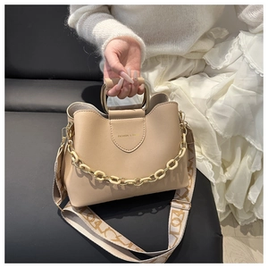 Dettaglio borsa beige con catena dorata e ampia tracolla decorata per uso quotidiano