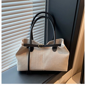 Detail of canvas tote bag with black leather straps and gold buckle on a windowsill