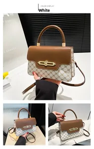 Close-up of white monogram canvas handbag with brown leather flap and gold clasp
