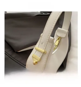 Detail view of white leather crescent bag with gold zipper and decorative metal buckle
