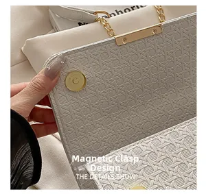 Detail view of woven texture small square bag with golden magnetic closure and chain