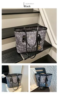 Détail du grand sac cabas à carreaux noirs avec pendentif M doré et logo de marque
