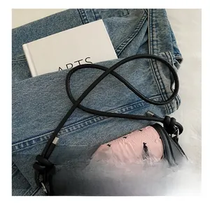 Gros plan d'un sac à bandoulière rose gaufré avec un nœud noir et des motifs floraux