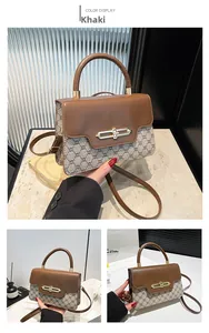 Macro view of khaki monogram canvas and brown leather crossbody bag with gold buckle