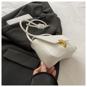 Detail of white wave-bottom bag featuring a sleek gold metal lock and knotted strap detail