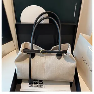 Minimalist canvas tote bag with black leather straps shown in premium gift packaging