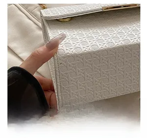 Macro shot of precise stitching and woven texture on a beige small square handbag